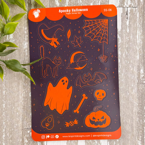 Sticker sheet labeled Spooky Halloween featuring orange Halloween-themed stickers, including a ghost, pumpkin, bat, cat, witch hat, spiderweb, bone, candy, skull, and stars, on a dark background. Green leaves border the left side.