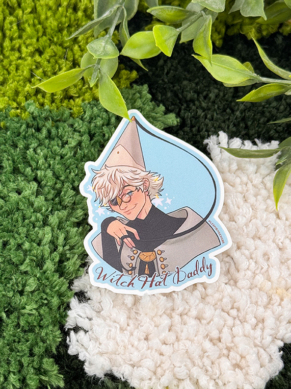 The Uppies Hamster ~ 3" Matte Vinyl Sticker features an illustrated hamster character with white hair, glasses, a tall pointed hat, and a cloak. The text "Witch Hat Daddy" appears over a textured green and white leafy background.