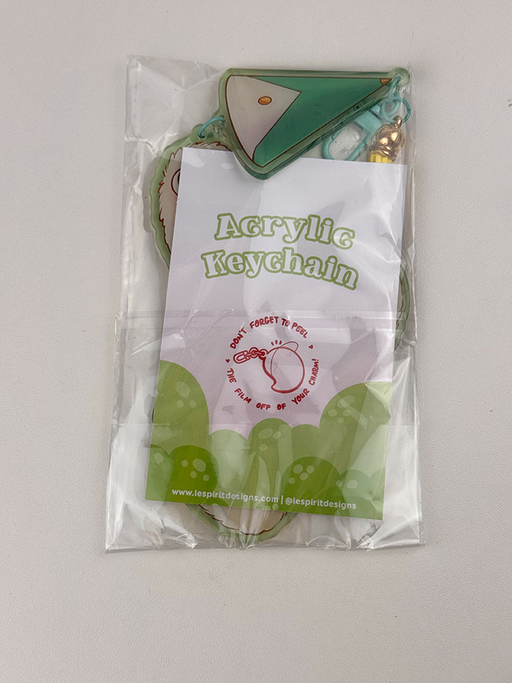 The Puffpuff ~ Acrylic Keychain comes in clear packaging with a label that says "Acrylic Keychain" and features a small illustration reminding users to peel off the protective film.
