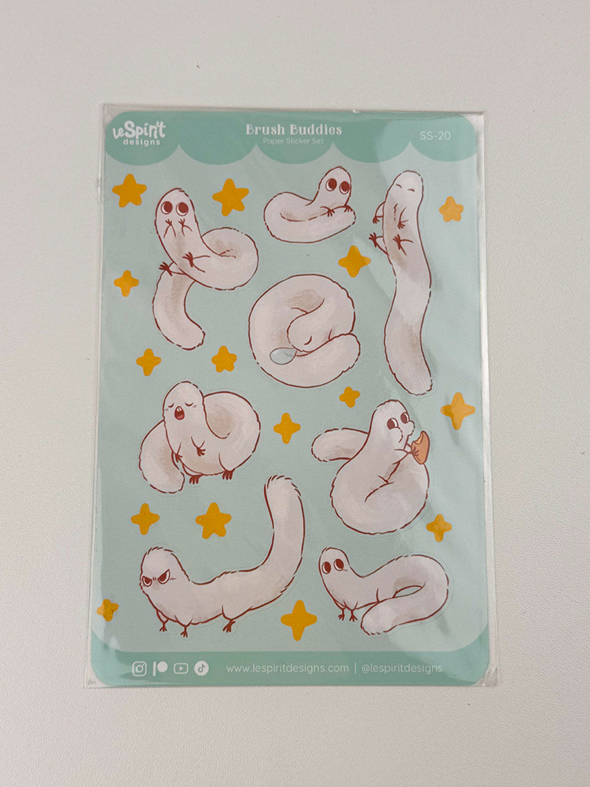 A Puffpuff ~ Paper Sticker Sheet with cute, white, worm-like creatures in various poses and small yellow stars on a light blue background. Designed by LeSpirit Designs.