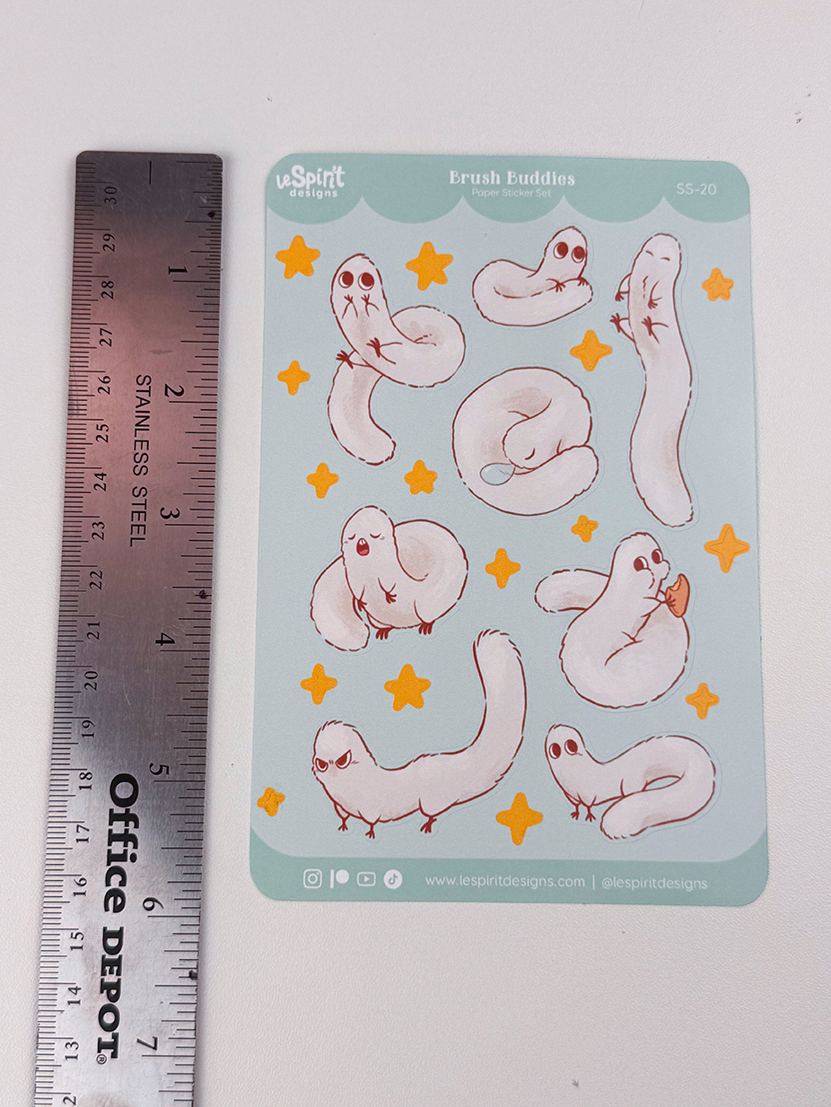 The Puffpuff ~ Paper Sticker Sheet features cute white snake-like creatures in different poses with yellow stars. A metal ruler indicates the stickers are approximately 4 inches tall.