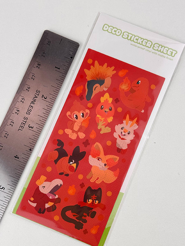 The Fire Starters ~ Deco Sticker Sheet is red and decorated with cute orange and brown cartoon animals, plus acorn and leaf motifs. A metal ruler beside it shows the size. The sheet is labeled “Deco Sticker Sheet.”.