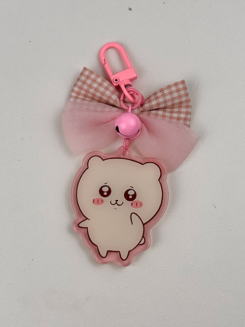 The Pink Hamster ~ Acrylic Keychain features an adorable cartoon hamster with blushing cheeks, a pink clip, a pink bell, and a brown-and-white checkered bow with a pink ribbon, displayed on a white background.