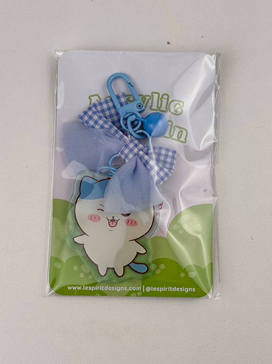 The Blue Kitty ~ Acrylic Keychain features a cute white cat with blue ears, bow, and clip, packaged on a green-accented card displaying lespritdesigns.com.