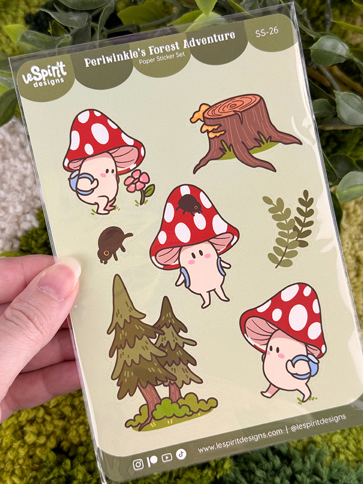A hand holds a sticker sheet featuring cute mushroom characters, a tree stump, a small black animal, leaves, and trees, with the label Periwinkles Forest Adventure at the top.