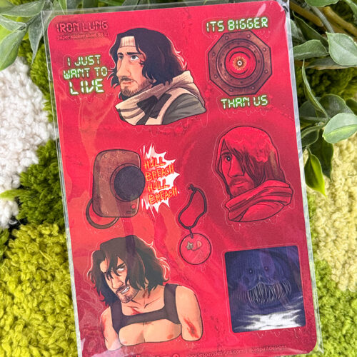 A sheet of red Iron Lung-themed stickers with illustrated characters, a submersible, quotes, and a round badge, placed on a textured green surface with some green plant leaves in the background.