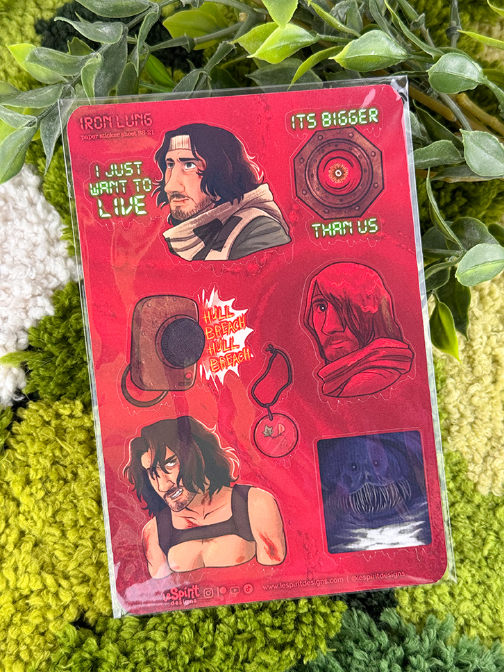 A sheet of red Iron Lung-themed stickers with illustrated characters, a submersible, quotes, and a round badge, placed on a textured green surface with some green plant leaves in the background.