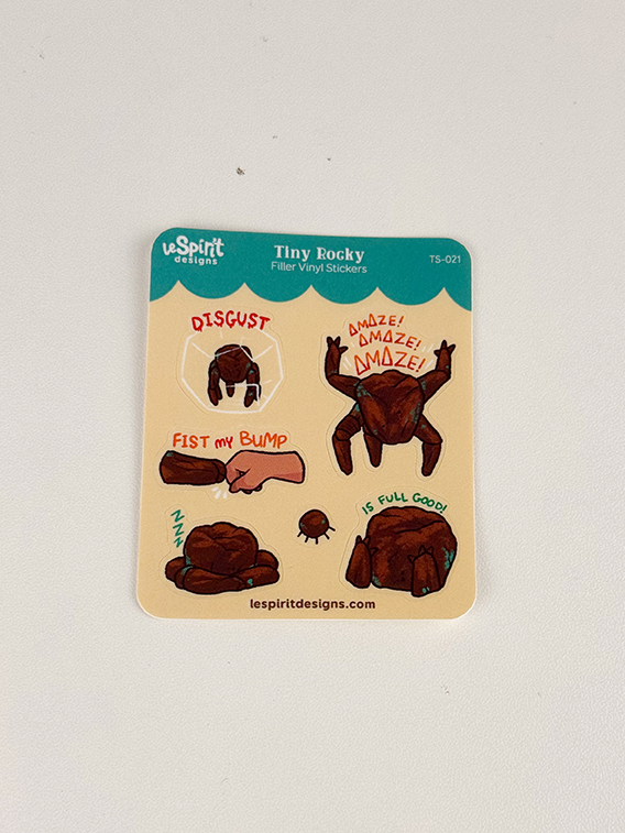 Tiny Rocky ~ Tiny Filler Vinyl Sticker Sheet featuring cartoon crabs expressing various emotions: one shows disgust, another excitement with “AMAZE!”, and a third labeled “Fist my bump.” Another crab exclaims “IS FULL GOOD!” Website link included at the bottom.