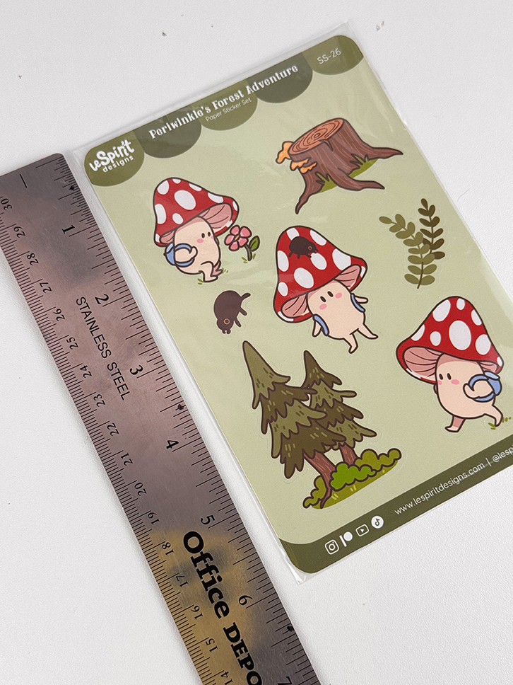 A ruler next to a sticker sheet featuring cute cartoon mushrooms with faces, a tree stump, a small animal, a tree, and some plants. The sticker sheet is labeled Porfriends Forest Adventure.